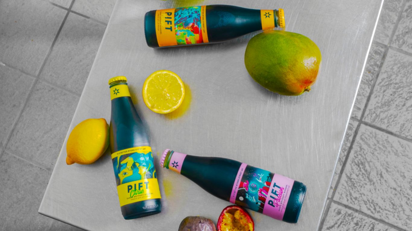 Pift varianter i flasker liggende med den tilsatte frugt, Passion, citrus og mango. 